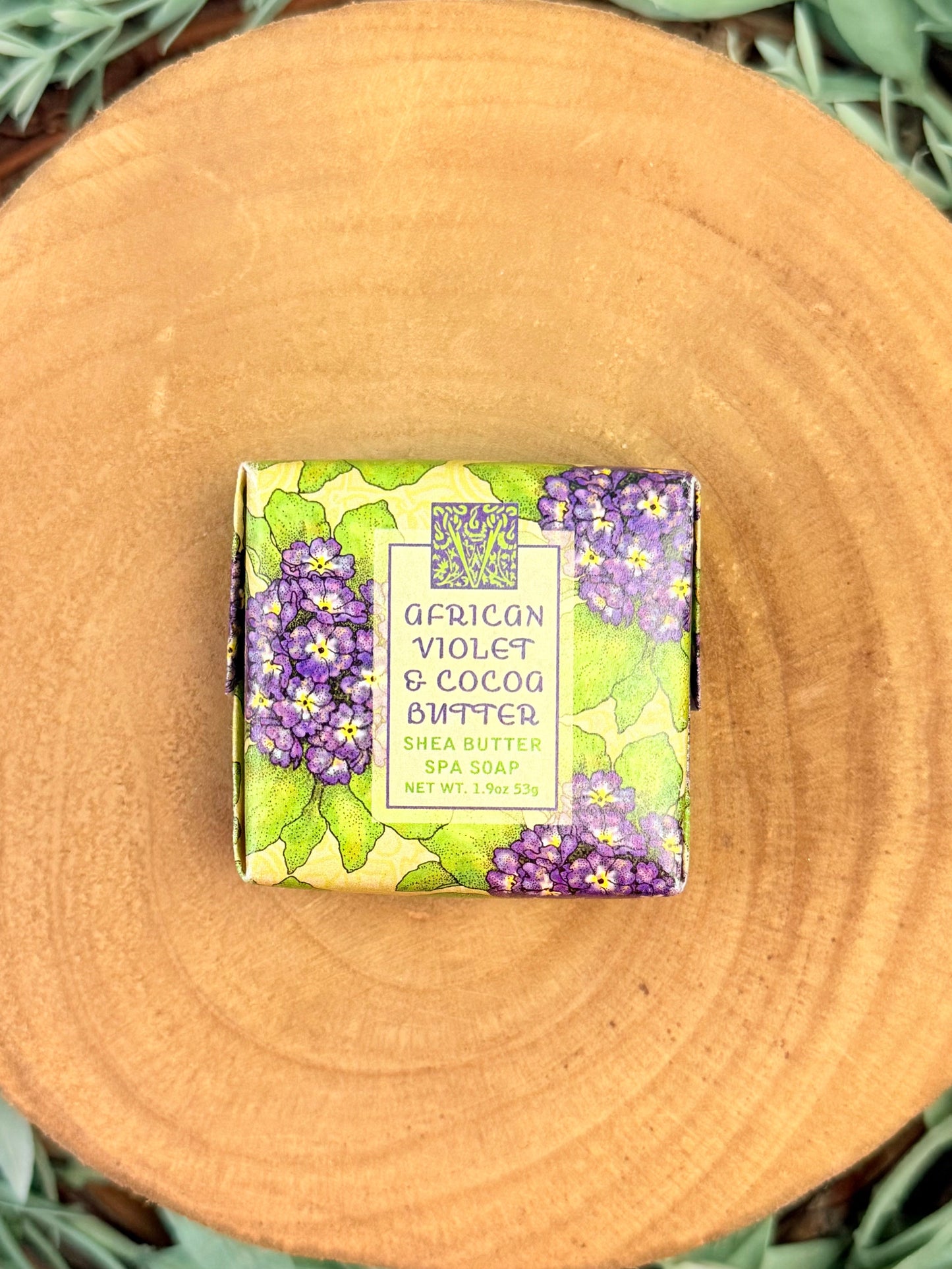 Bar of soap with a decorative purple and green label on a wooden surface