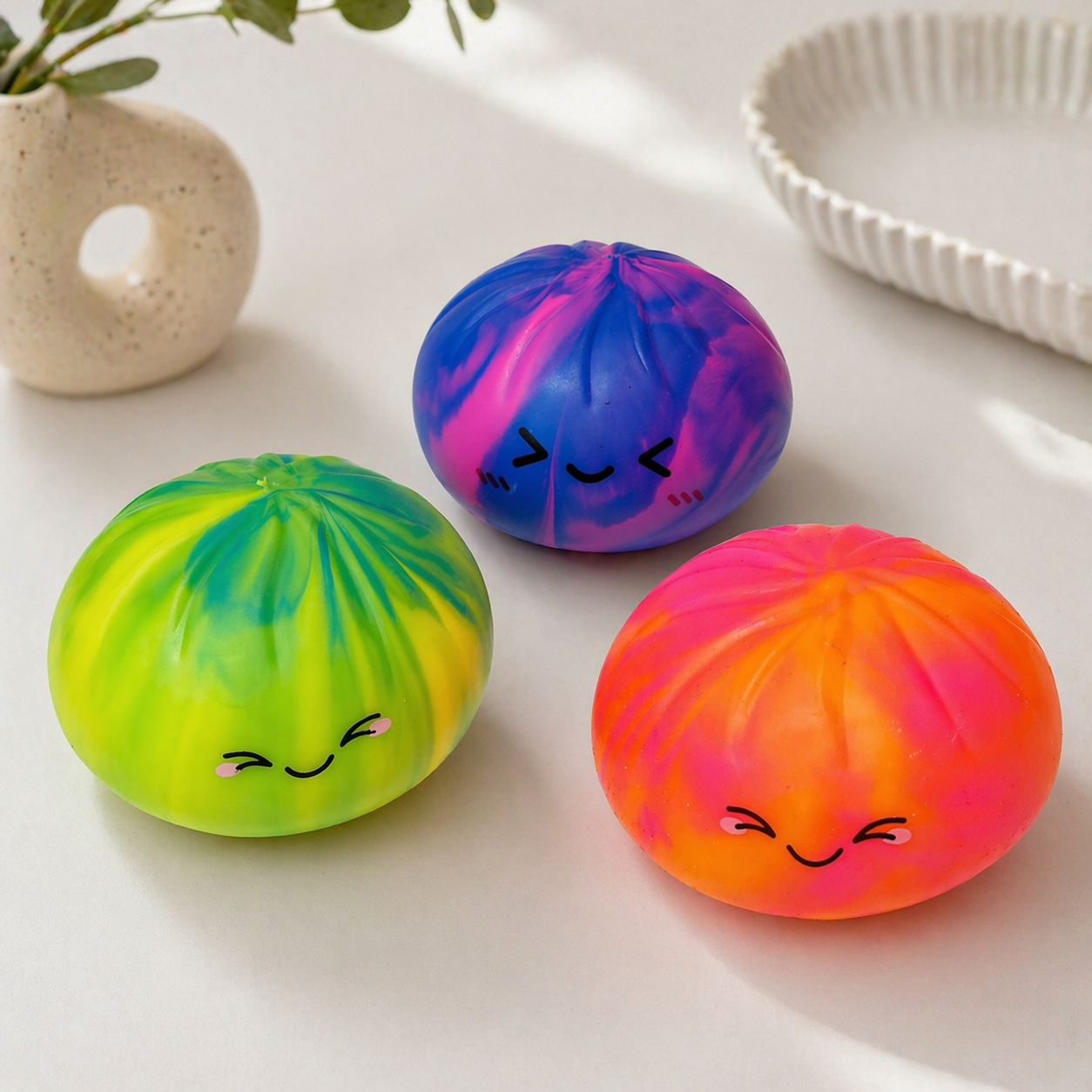 Three colorful marbled dumplings with smiling faces on a light surface.