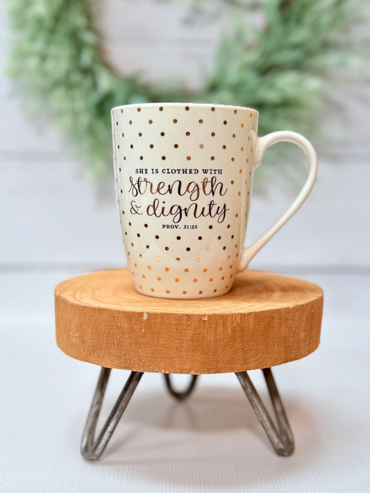 Strength and Dignity coffee mug with gold polka dot design styled on a wooden stool with greenery background