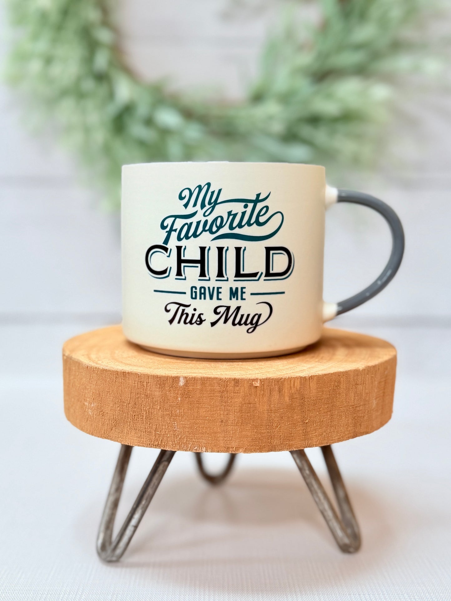 Favorite Child ceramic coffee mug with black lettering on white mug styled on wood stool
