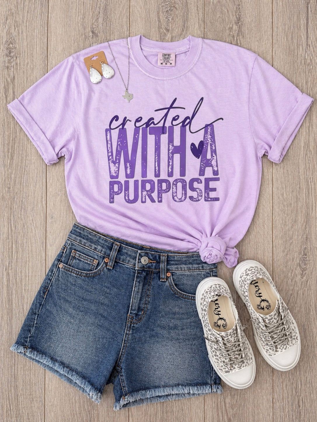 Lavender created with a purpose graphic tee styled with denim shorts and sneakers flat lay
