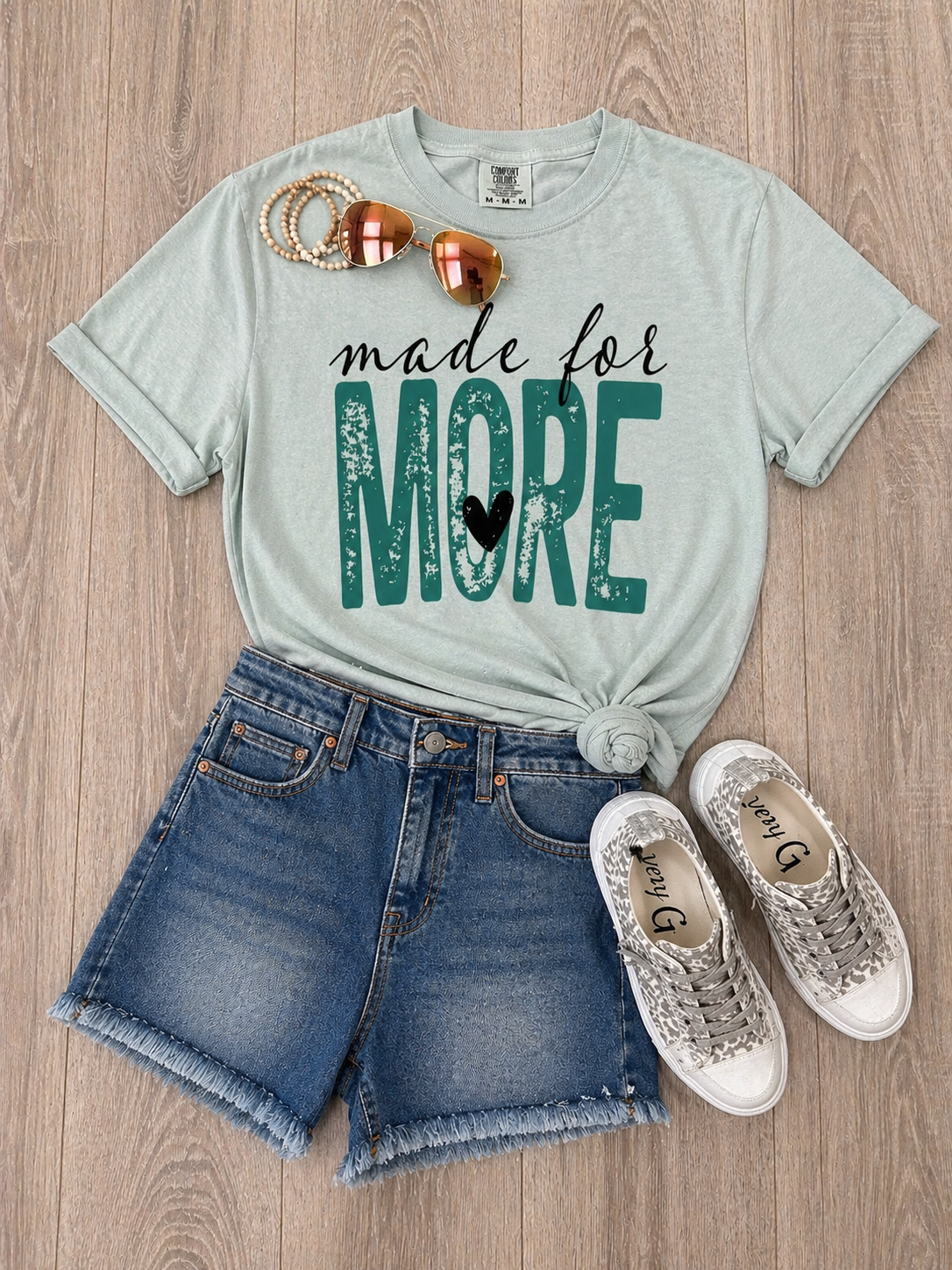 Sage green Made for More graphic tee styled with denim shorts and sneakers flat lay