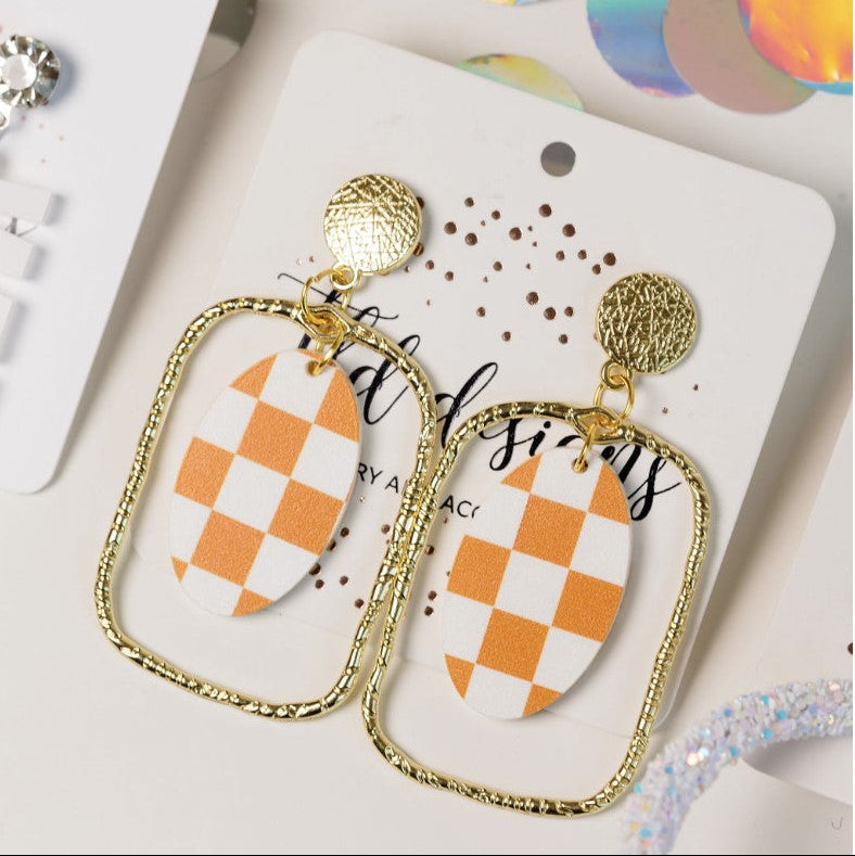 Pair of checkered earrings on a branded card with colorful confetti in the background